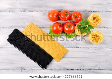 cuttlefish ink pasta and egg pasta with tomatoes on a white wooden background