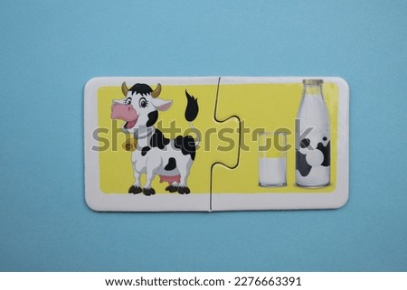 Cow and milk picture puzzles, cow and milk picture puzzle placed over blue background.