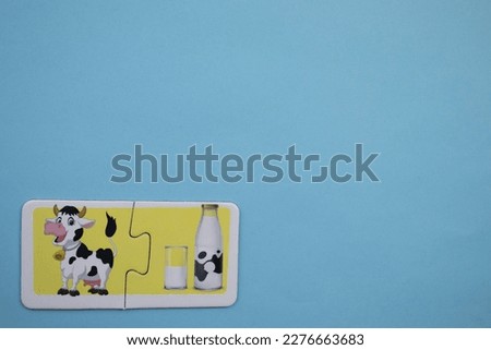 Cow and milk picture puzzles, cow and milk picture puzzle placed on the left over blue background.