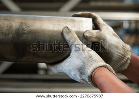 employee lifting a large round bar in an industrial factory