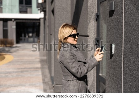 female entering secret key code for getting access and passing building using application on mobile phone, woman pressing buttons on control panel for disarming smart home system Royalty-Free Stock Photo #2276689591