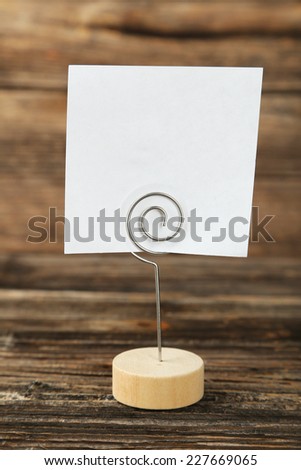 White note paper on a holder on brown wooden background