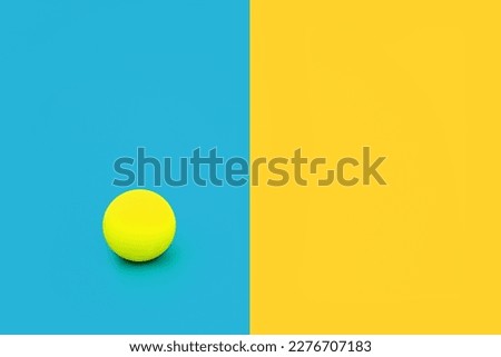 Dare to be different and independent concept with vivid blue and yellow contrast background with ball. Minimal solitary, alone, leadership, stand out in a crowd composition. Flat lay, copy space.

