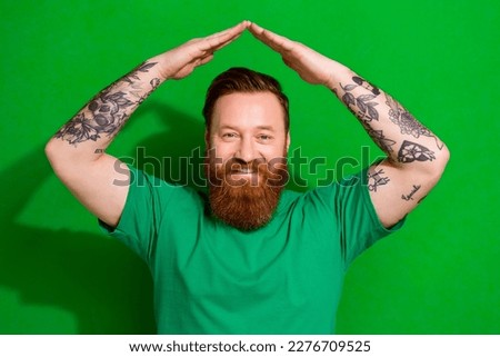 Photo of funky cool guy dressed t-shirt smiling showing arms roof isolated green color background Royalty-Free Stock Photo #2276709525