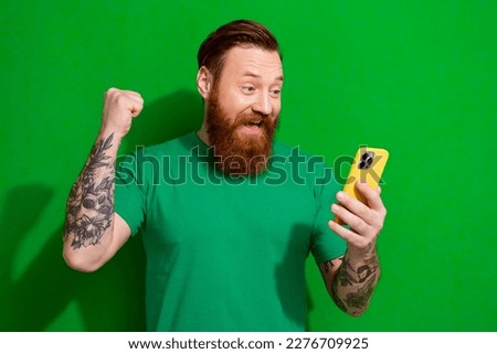 Photo of lucky funky guy dressed t-shirt rising fist egame apple samsung modern gadget isolated green color background