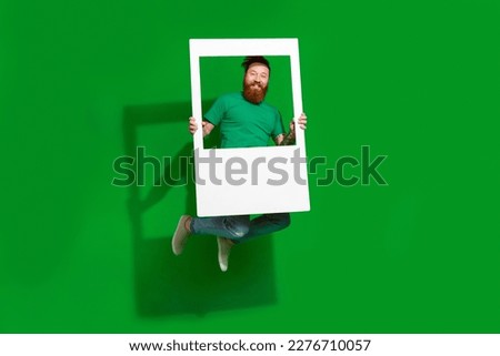 Full body portrait of active cheerful person jumping hands hold paper album card isolated on green color background