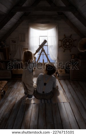 Children play in the attic of their house. Imagine themselves as tourists, explorers. Look through a telescope, study a world map, play in a makeshift tourist tent. Dreaming of travel and adventure. Royalty-Free Stock Photo #2276715101
