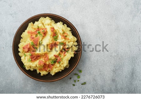 Mashed boiled potatoes. Bacon mashed potatoes with green onion, pepper and cheddar cheese in bowl on light old wooden backgrounds. Delicious creamy mashed potatoes. Top view. Royalty-Free Stock Photo #2276726073
