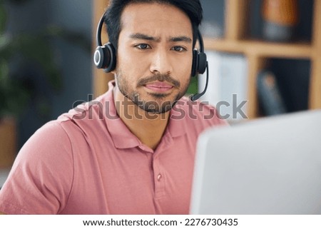 Serious asian man, call center and computer with headphones for customer service, help or support at office. Focused male consultant or agent with headset on PC for telemarketing or online advice Royalty-Free Stock Photo #2276730435