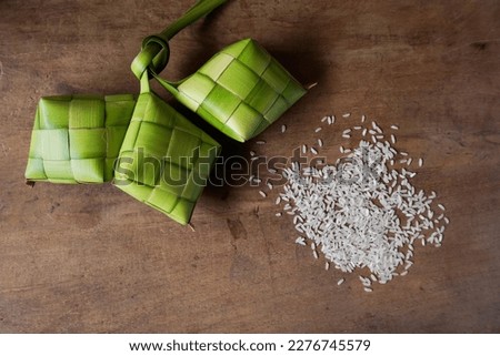 Close up view of Ketupat and rice, an Indonesian traditional cuisine very popular during Hari Raya Idul Fitri. Ketupat is a natural rice casing made from young coconut leaves for cooking rice. Royalty-Free Stock Photo #2276745579