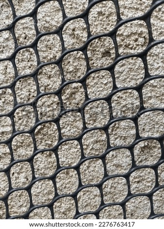 A close-up of a wall with a black plastic mesh.  Textured Wall and Fence, Background, Wallpaper, JPEG