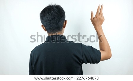 Adult Asian man wearing a black T-shirt turns his back to the camera and points his finger upwards. Not caring. The goodbye gesture