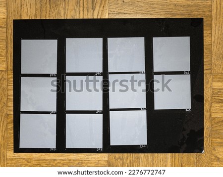 original blank print of black and white hand copy contact sheet with empty film frames on wooden floor. 120 film photo placeholder. cover or poster idea.