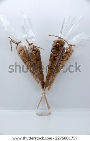 Almonds and peanuts in a transparent package on a gray-white background.