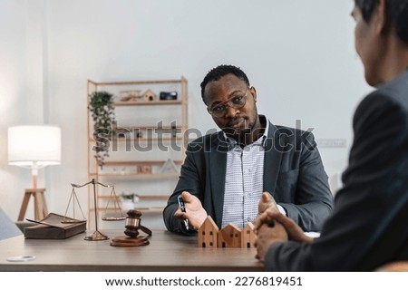 Contemporary lawyer explaining terms and conditions of mortgage contract to young African man sitting in front of him
