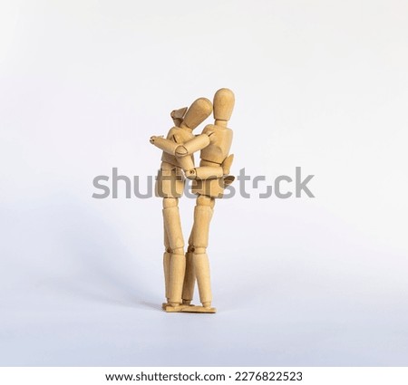 two wooden mannequins as friends or lovers hugging each other