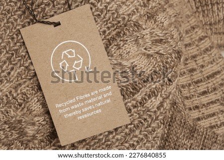 Close up of clothing tag with recycle icon. Recycling products concept. Zero waste, suistainale production, environment care and reuse concept. Royalty-Free Stock Photo #2276840855