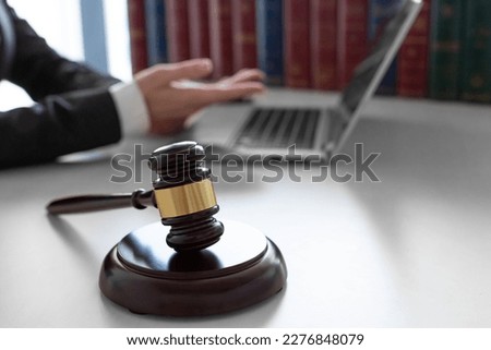 A female judge during an online trial. Video call in front of laptop monitor. Cropped photo of a blurred female hands gesturing in front of laptop monitor. Focus on the judge's gavel.