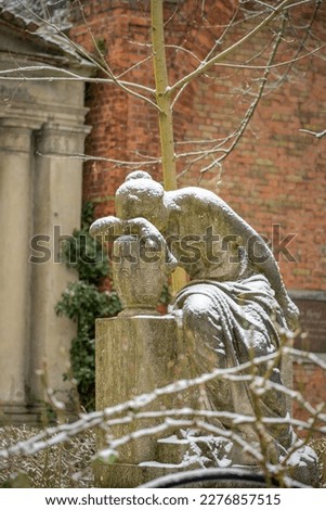 Snow covered statue of a mourning woman at the snowy "Alter Luisenstädtischer Friedhof" cemetery in Berlin-Kreuzberg