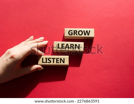 Grow Learn Listen symbol. Concept words Grow Learn Listen on wooden blocks. Businessman hand. Beautiful red background. Business and Grow Learn Listen concept. Copy space