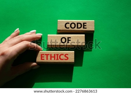 Code of ethics symbol. Concept words Code of ethics on wooden blocks. Beautiful green background. Businessman hand. Business and Code of ethics concept. Copy space.