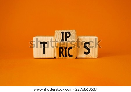 Tips and Tricks symbol. Turned wooden cubes with words Tricks and Tips. Beautiful orange background. Business and Tips and Tricks concept. Copy space