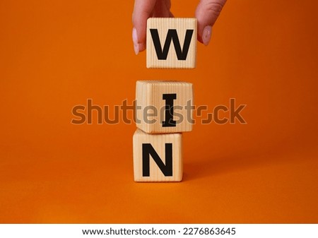 Win symbol. Wooden blocks with words Win. Businessman hand. Beautiful orange background. Business and Win concept. Copy space. Royalty-Free Stock Photo #2276863645