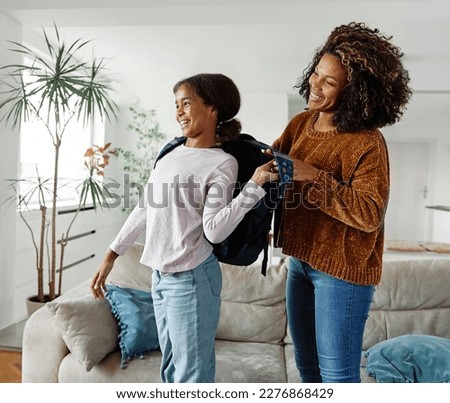 Mother helping daughter to get ready for school, helping her with backpack and books,hugging and leaving home  Royalty-Free Stock Photo #2276868429