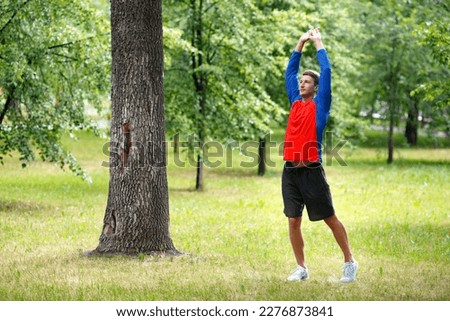 Photo of a man stretcing muscles outdoor - sport and healthy lifestyle concept. Workout in city park.