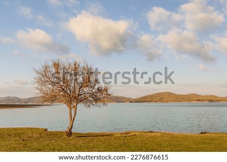 Beautiful landscape view of Lake Plastiras in Karditsa, Greece. Lake Plastiras view on Autumn Sunset with trees and cloudy sky for background.
