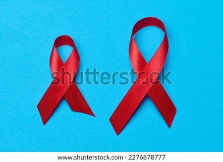 A silk red ribbon in the form of a bow on a blue background, a symbol of the fight against AIDS and a sign of solidarity and support
