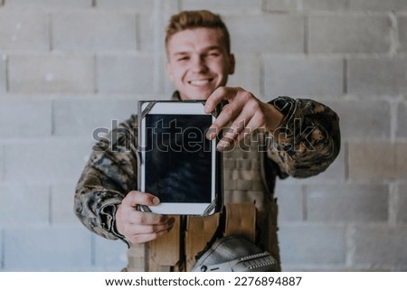 Soldier using tablet computer against old brick wall