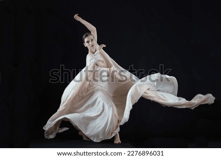 A dancer in a white robe on a black background. Royalty-Free Stock Photo #2276896031