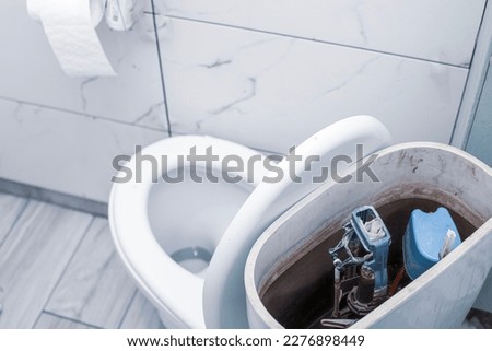 open toilet cistern when flush system breaks down, dirty poorly paid plumbing job Royalty-Free Stock Photo #2276898449