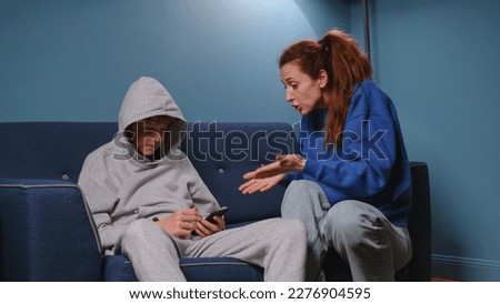 Mom screams and scolds her son in the room on the blue sofa. Irritated woman teaches a lesson to a teenager. The boy has a difficult adolescence. Child abuse in the family Royalty-Free Stock Photo #2276904595