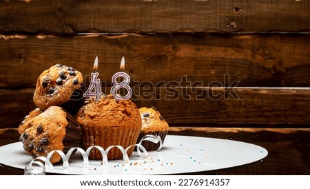 Pies with a number 48  of candles burning for the anniversary. Copy space background happy birthday on wooden background. Card or postcard festive rustic brown.