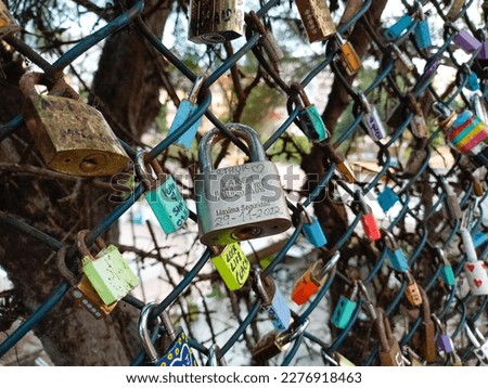 Many padlocks with the names of couples attached to a metal mesh.