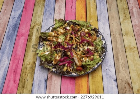 Appealing crispy breaded fried chicken salad with lettuce, cherry tomatoes, red onion and sweet corn