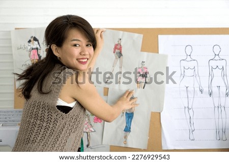 Young fashion designer paste pattern for cloth on cork board. Asian woman working in home base cloth design business.