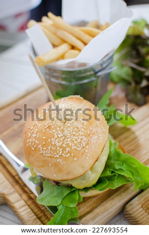 Hamburger with juicy beef and cheese with potato and vegetables salad