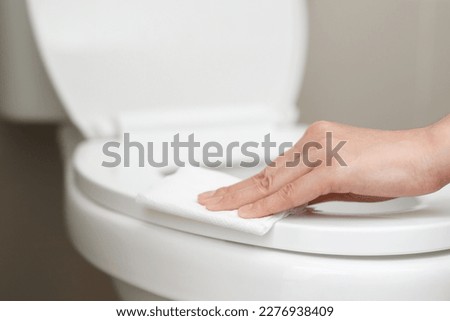 woman using tissue paper clean the toilet in the bathroom at home. Royalty-Free Stock Photo #2276938409