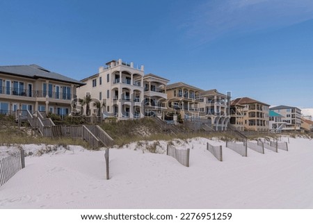 Multi-storey beach houses against clear blue sky in Destin Florida. Coastal landscape with waterfront homes overlooking the sandy shore and ocean. Royalty-Free Stock Photo #2276951259
