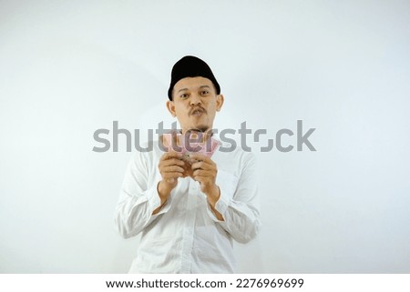 Asian muslim man smiling happy while holding paper money over white background