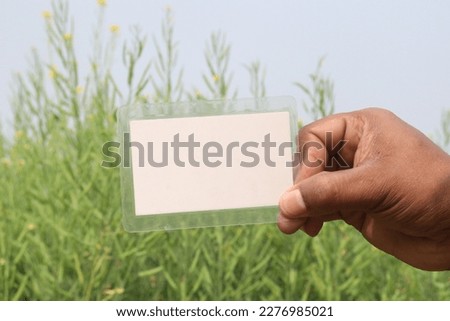 white colored sign card on hand with mustard farm for any text