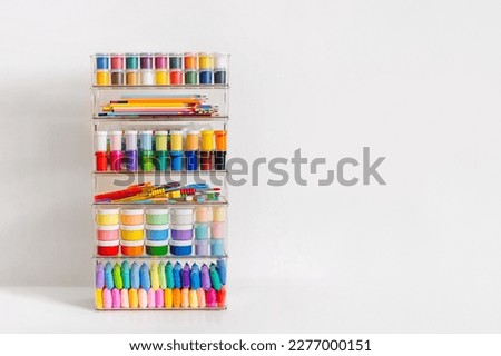 Paints, pencils, plasticine and various material for creativity and kids art activity in containers on shelves. Stationery and supplies for drawing and craft. Organizing and storage craft room. Royalty-Free Stock Photo #2277000151