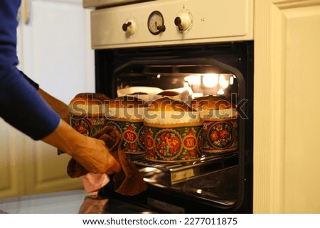 A woman prepares Easter cakes at home, the girl kneaded the dough, poured into molds and put Easter cakes in the oven, traditional baking Easter cakes with her family at home