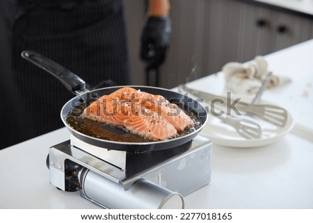 chef cooking salmon steaks in the kitchen Royalty-Free Stock Photo #2277018165