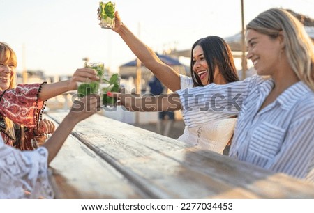 Group of multiracial friends at sunset enjoying their holiday together as they toasting to summer and fun