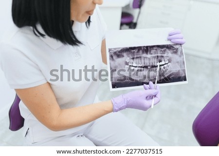 Dentist explaining the details of a x-ray teeth picture to his patient in clinic. Oral care, orthodontics