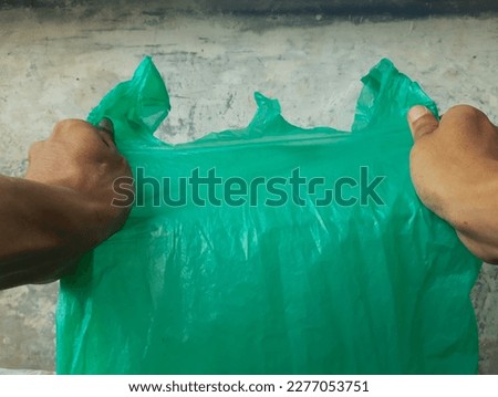 two hands pinching, squeezing, stretching and picking up green plastic waste as a background for a website, article, or photojournalism.